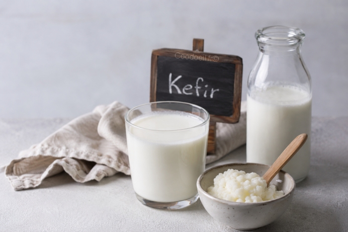 Verre de k&eacute;fir frais accompagn&eacute; de grains de k&eacute;fir et d'une bouteille en verre, illustrant cette boisson ferment&eacute;e r&eacute;put&eacute;e pour ses bienfaits sur le microbiote intestinal et la digestion.